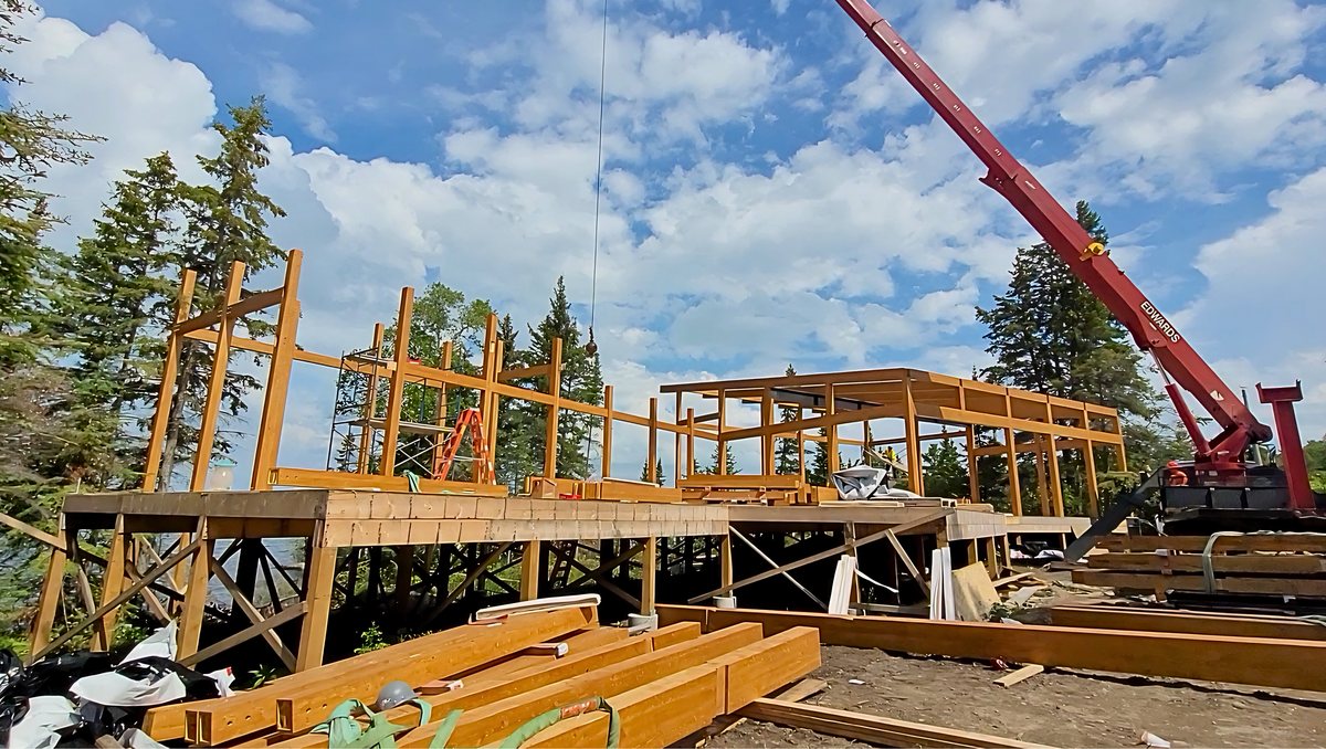 Timber frame raised by crane at a remote lakeside build