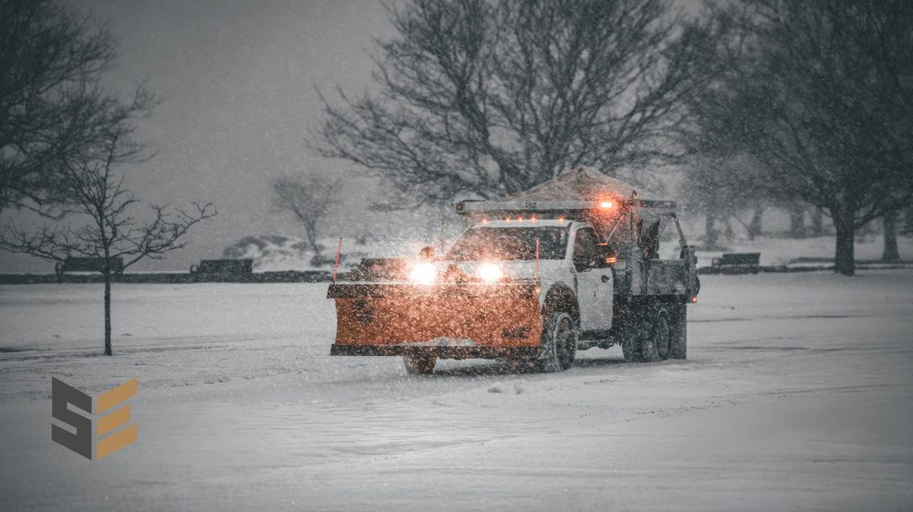 SilverEdge plow truck clearing a lot during snowfall with beacons on